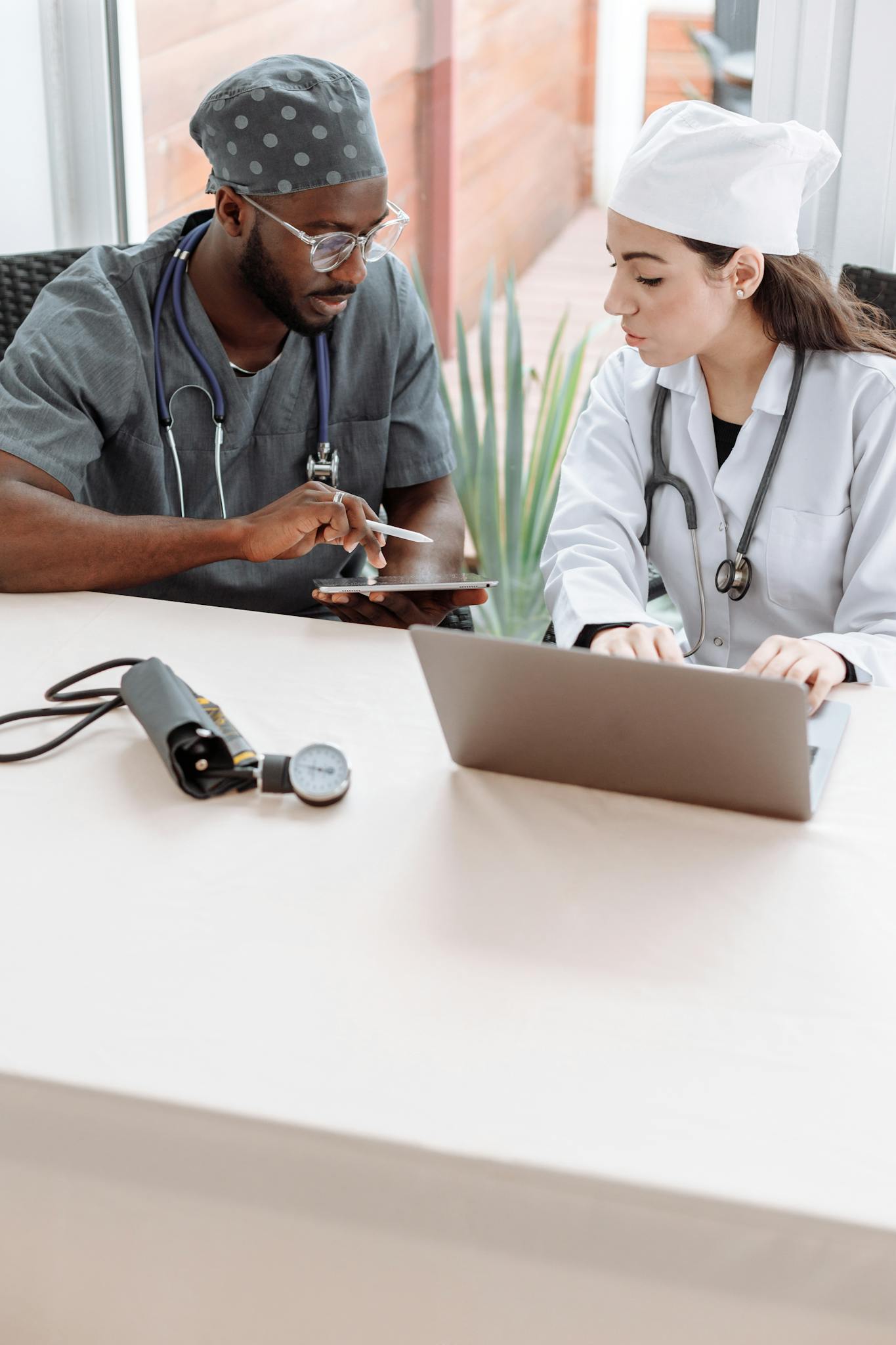 Medical Professionals Looking at the Screen of the Tablet while Sitting Next to Each Other